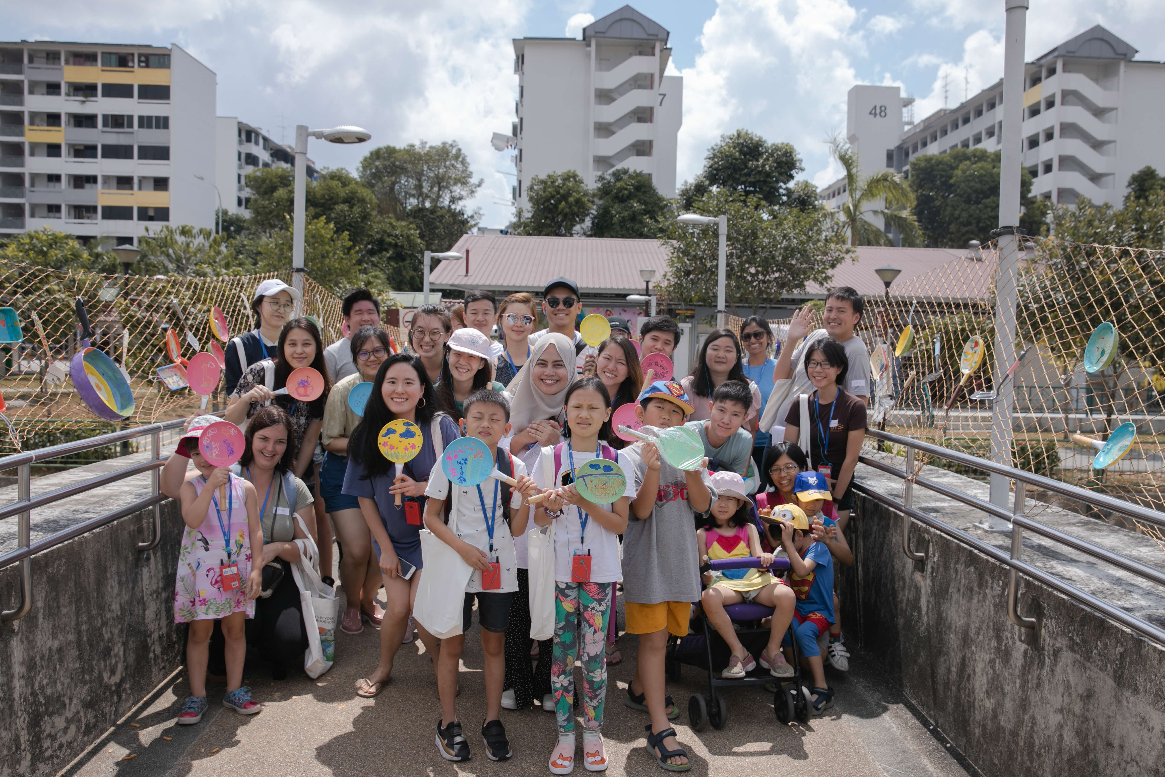 A group of kids and adults posing for a group photo on a bridge.